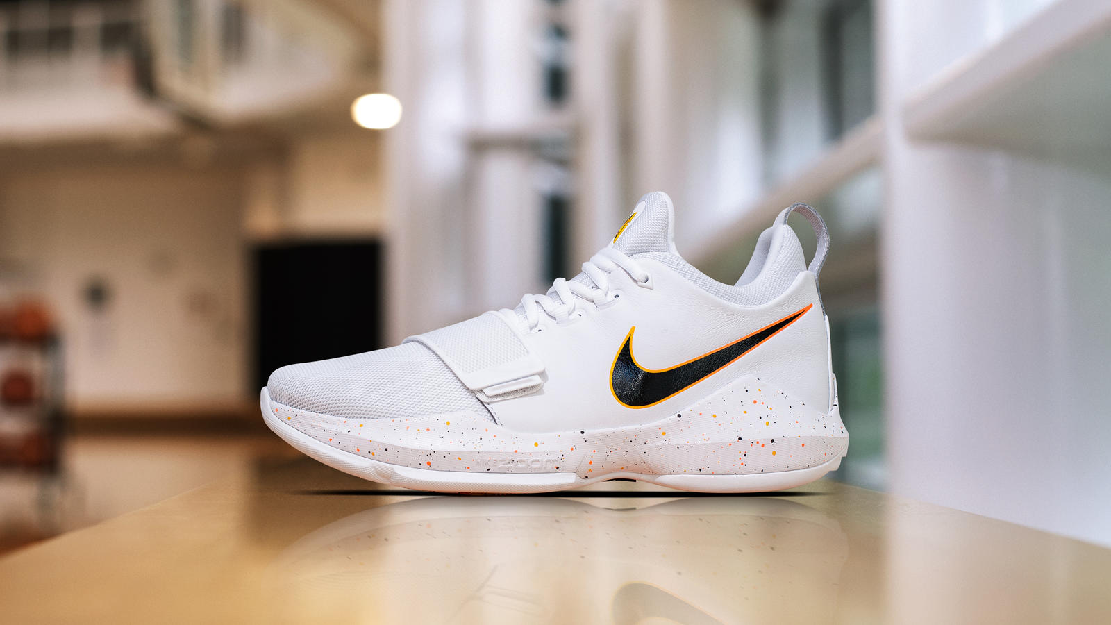 Nike's Paul George basketball shoes in white with a black and orange swoosh.