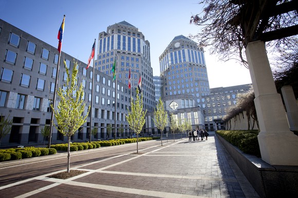 Picture of entrance to P&G's corporate worldwide headquarters, with trees, flags, and small hedges in the foreground.