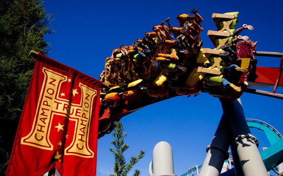 Dragon Challenge's "fire" coaster riding by a True Champion banner.