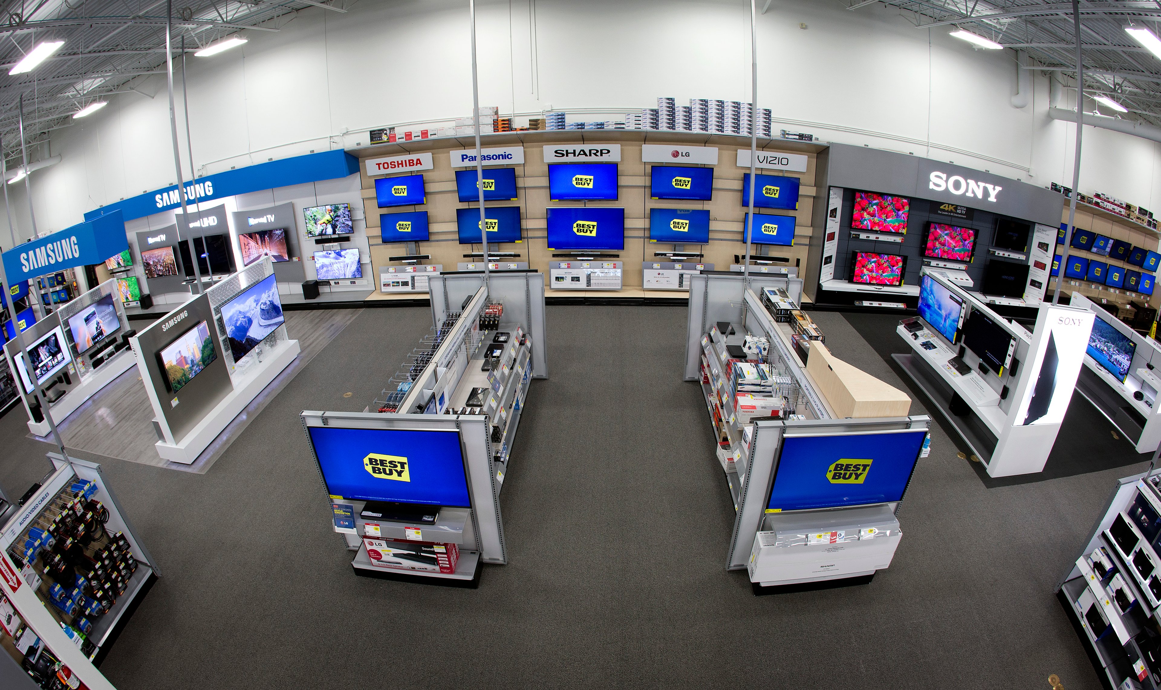 A view of a Best Buy home theater department, with TVs displayed on the wall and on two end caps.