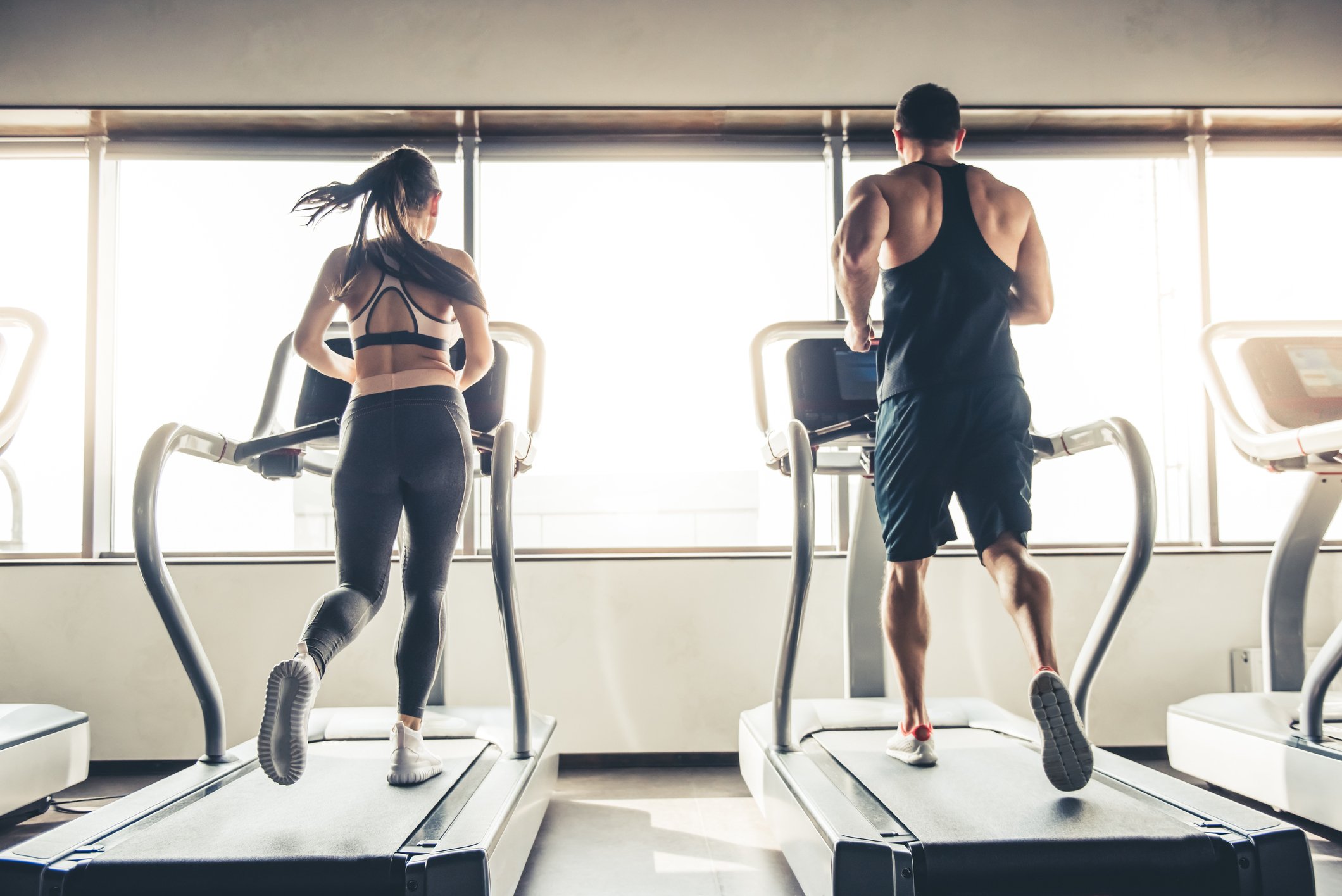 Woman and man running on a treadmill in a fitness gym