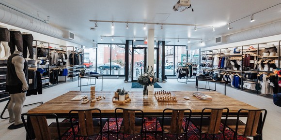 Inside a Lululemon store with a table and chairs in the foreground and merchandise on shelves to the left and right side.