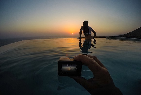 Person holding camera taking a picture of a woman at sunset