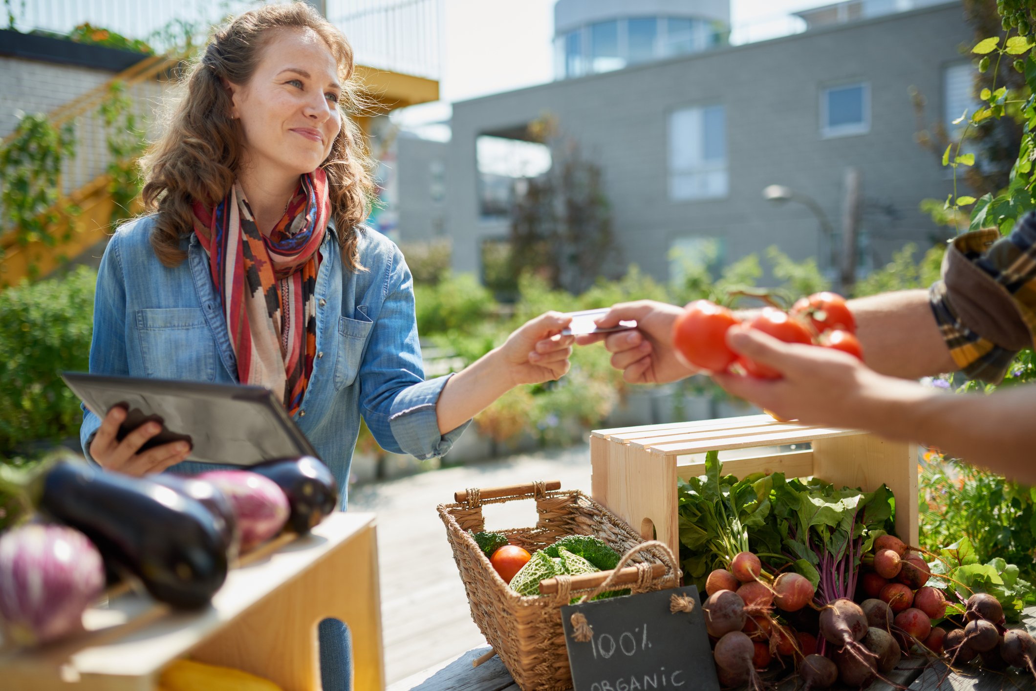 Woman buying produce from a farmers' market vendor.