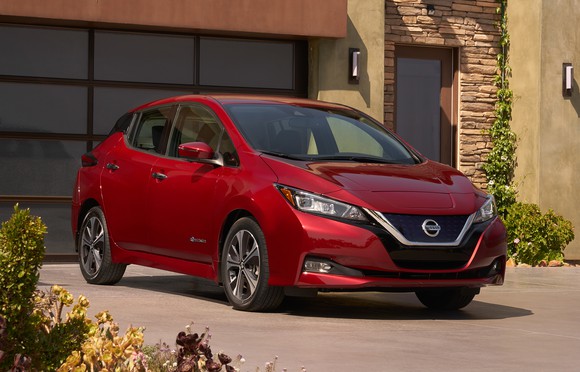 A red 2018 Nissan Leaf in a suburban driveway.