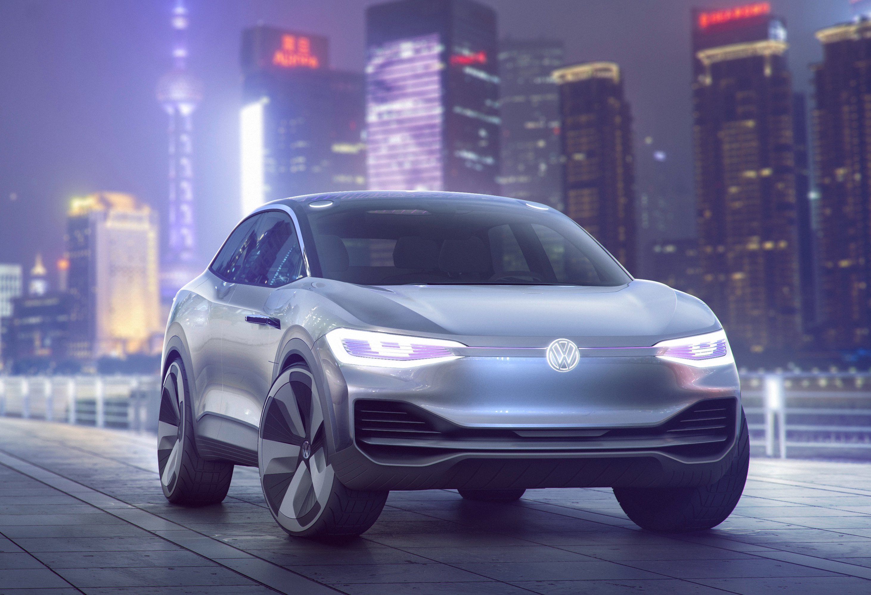 The first VW I.D. Crozz show car, a futuristic-looking silver SUV, is shown at night with Shanghai's skyline in the background.