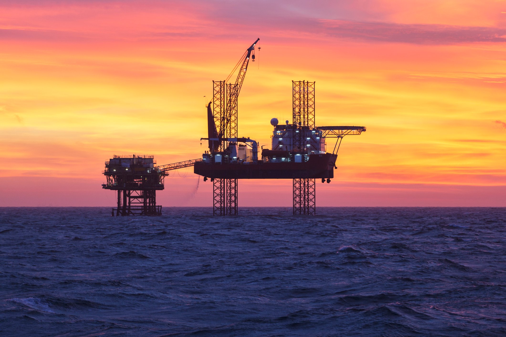Offshore oil rig in open water at sunset