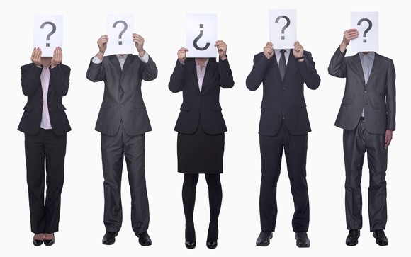 Five people dressed in business attire holding signs with question marks over their faces