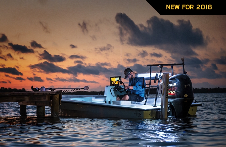 A fisherman sitting in a boat in the water with a sunset in the background.