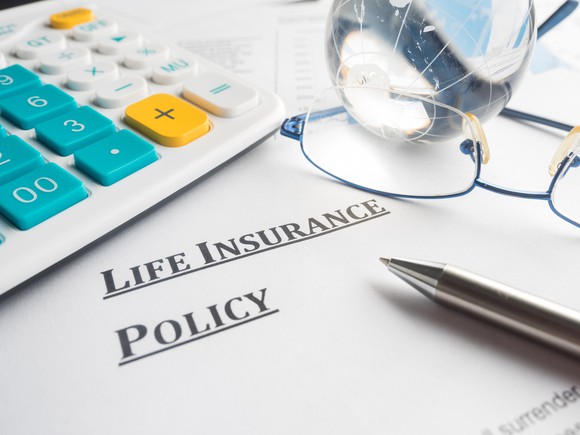 A life insurance policy with a pen and pair of eyeglasses on top of it