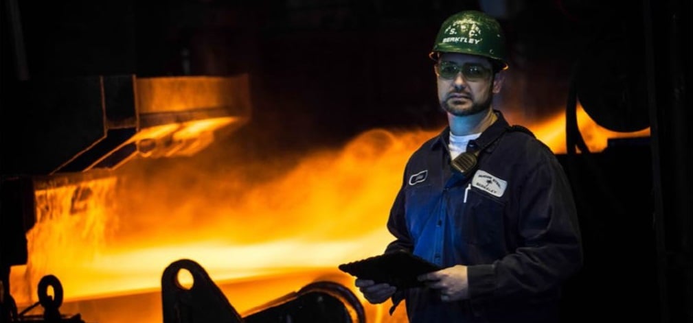 Nucor employee in front of a steel mill.