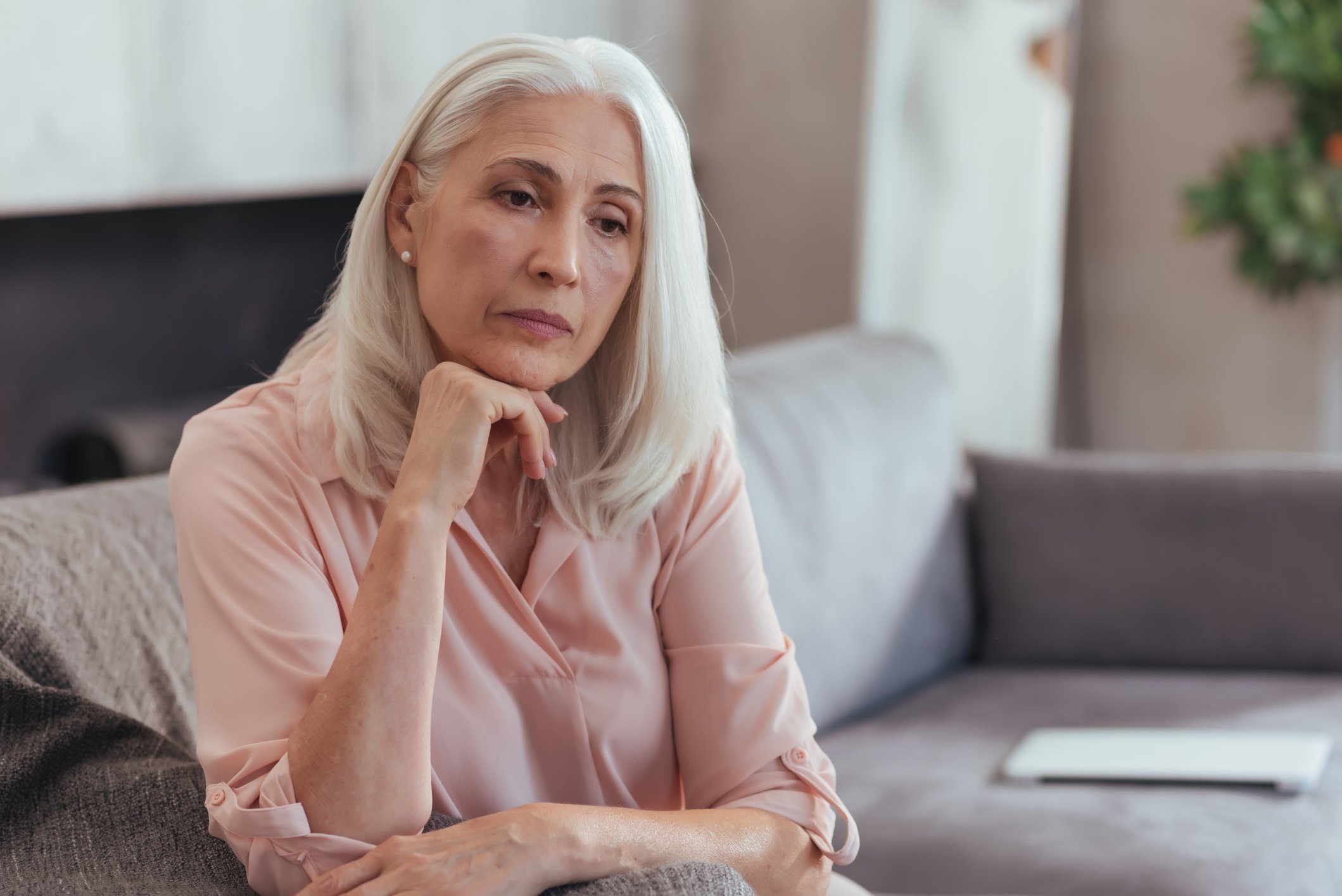 Older woman seated with hand under her chin in seemingly deep thought