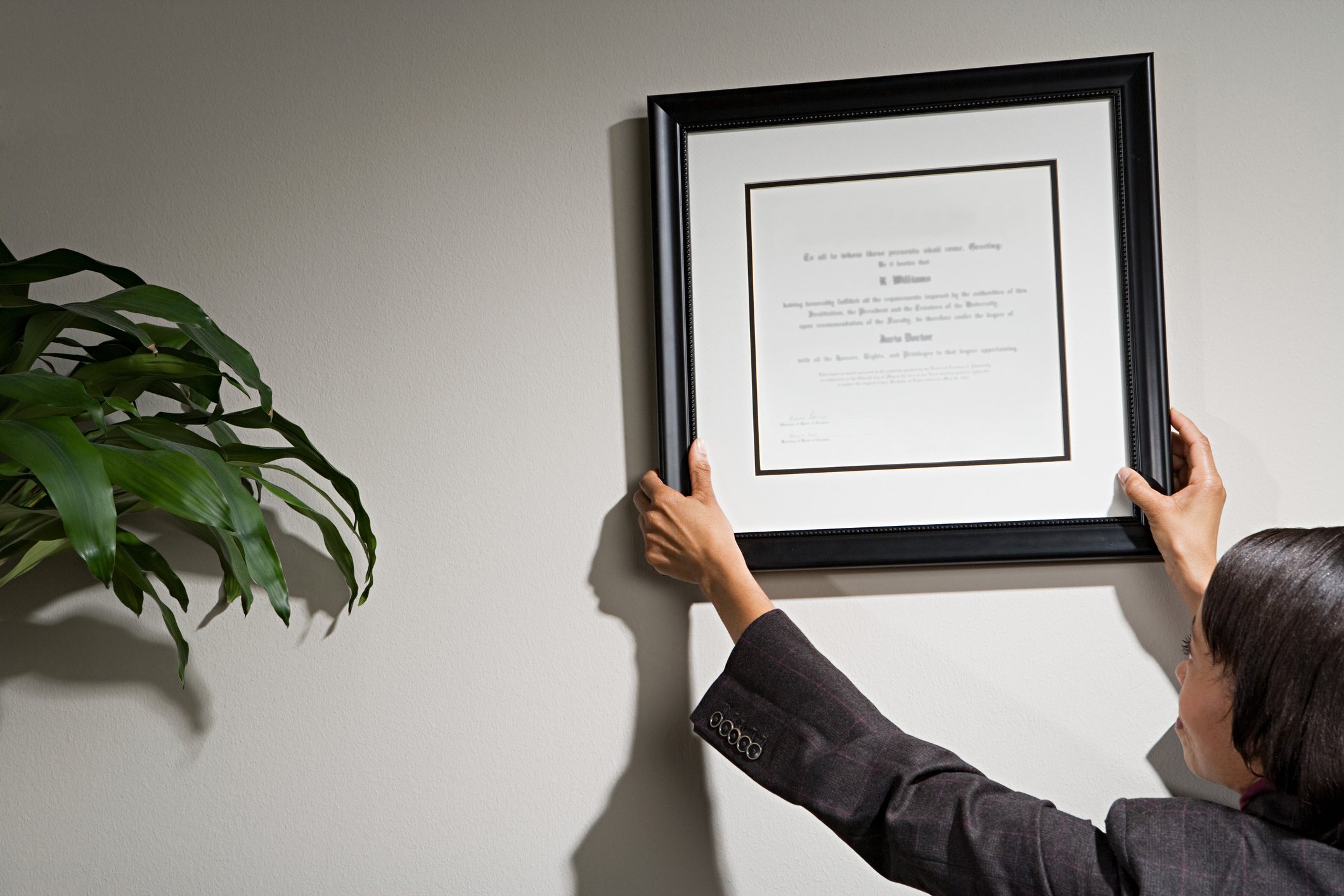 Woman hanging framed certificate on wall