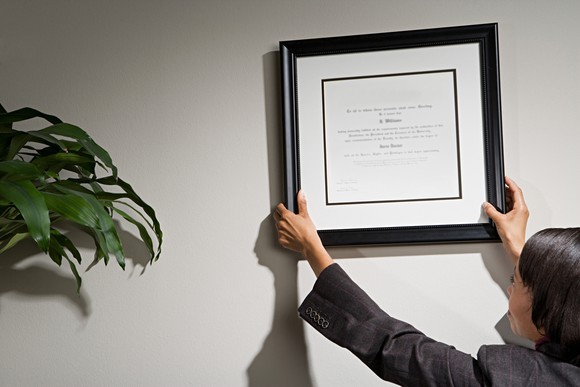 Woman hanging framed certificate on wall