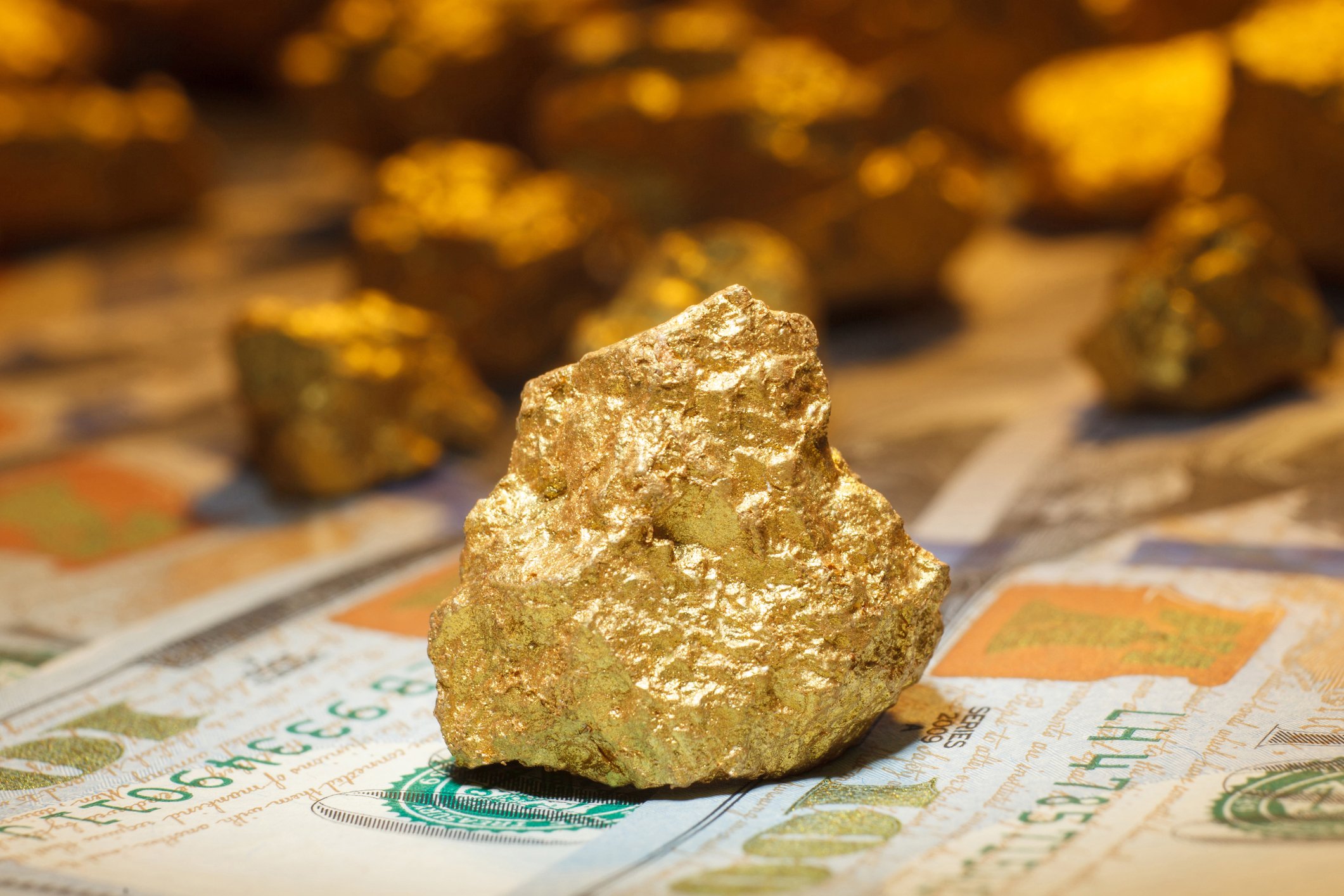 A big gold nugget on $100 bills.