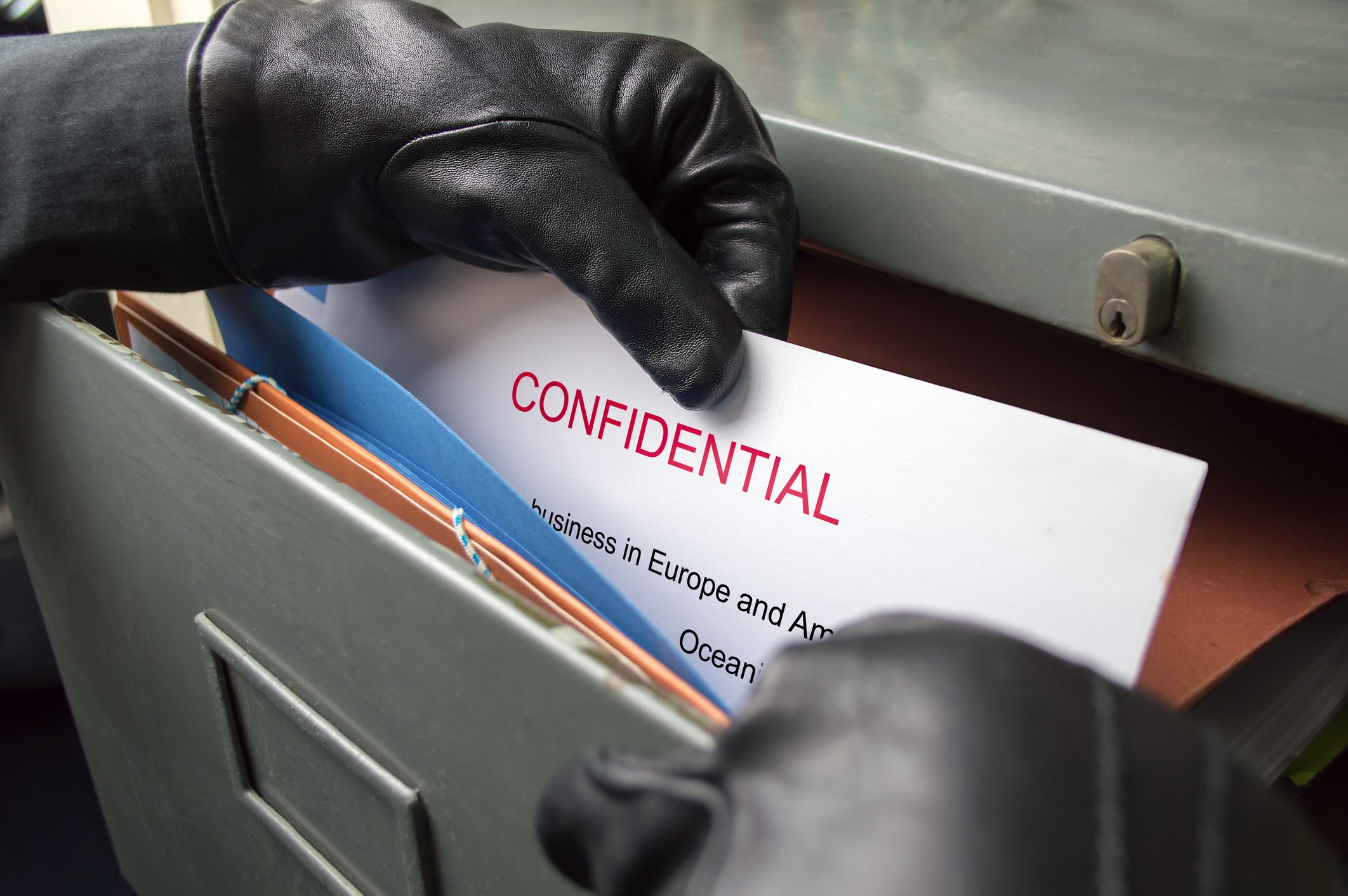A man steals confidential documents from a filing cabinet.