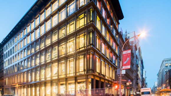 Nike's five story New York Soho district store all lit up against a fading blue sky as night comes.