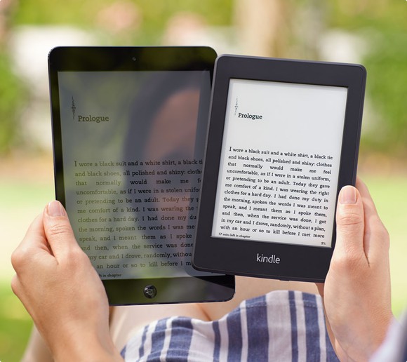 A woman's reflection is seen in a Kindle screen, as she holds it next to an Amazon Kindle Paperwhite, which shows no reflection.
