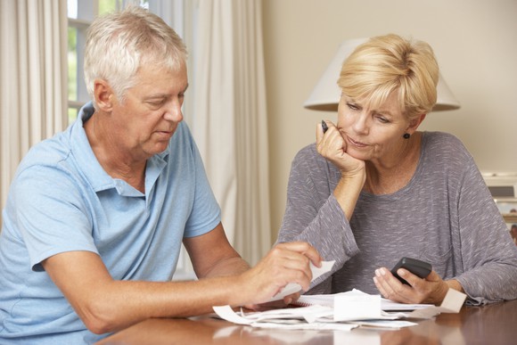Older couple reviewing papers at a table, looking serious