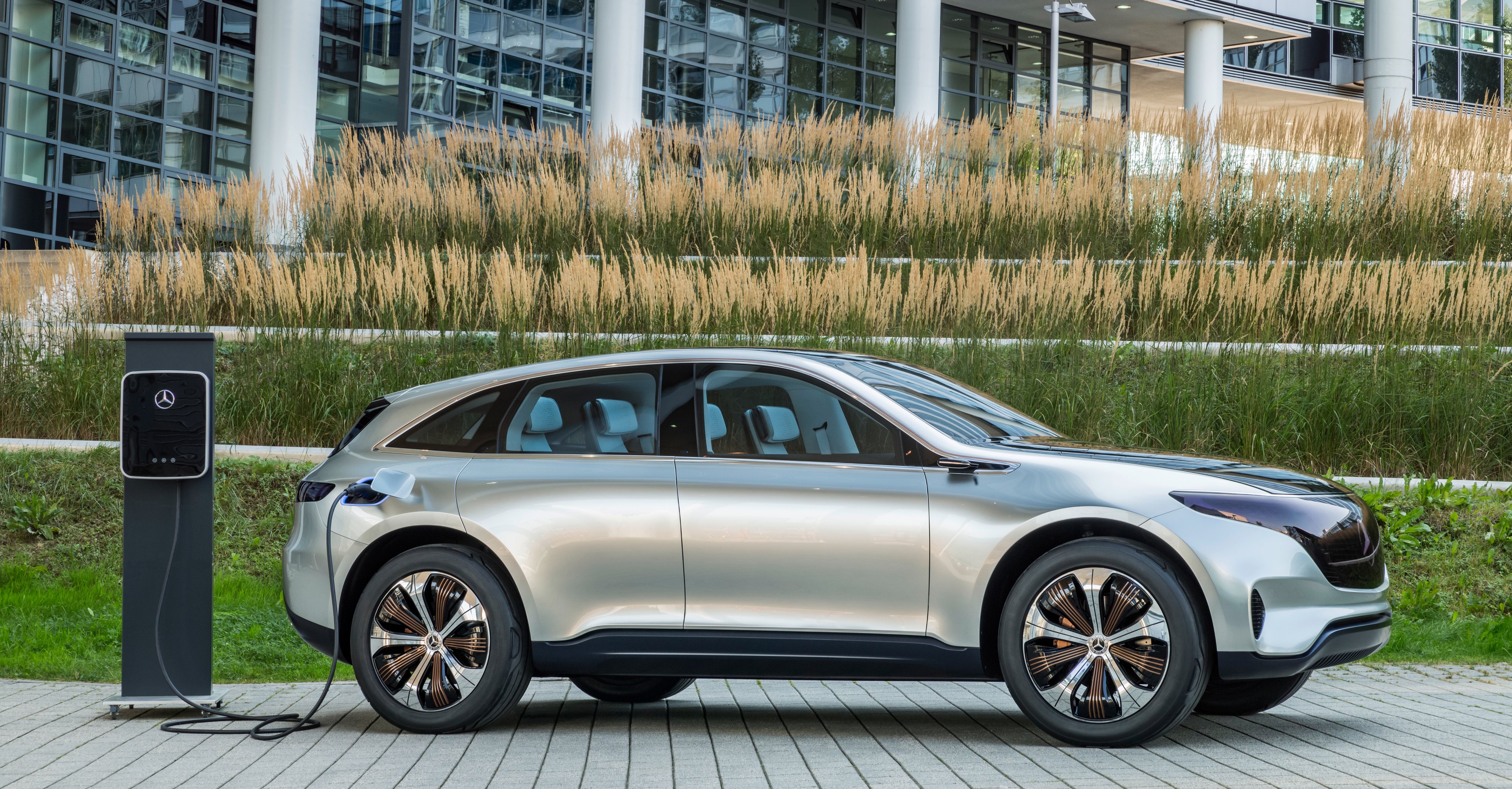 The Mercedes-Benz Generation EQ Concept, a silver SUV, next to a recharging station.