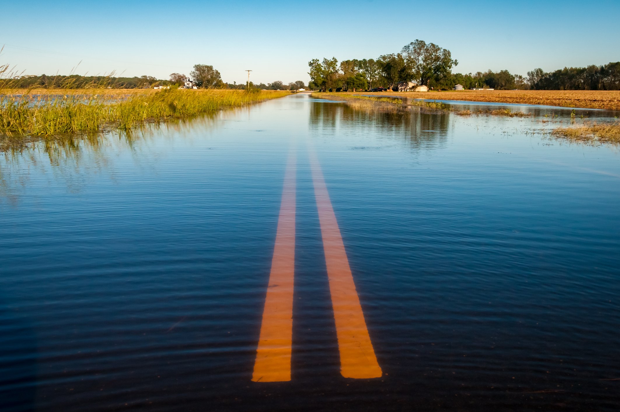 A flooded two-lane road stretching out into the distance.