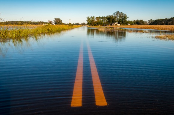 A flooded two-lane road stretching out into the distance.