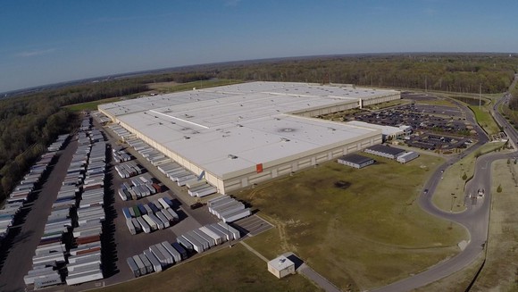 Ariel view of a large industrial building with a flat roof and lots of trailers in the lot and in the doors of the distribution center.