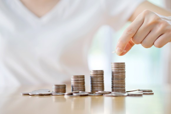A woman stacking coins in piles of increasing height.