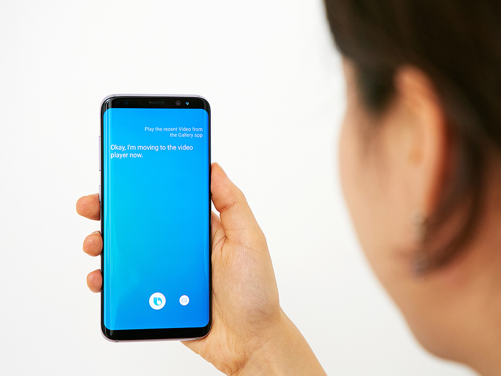 A woman holding the Galaxy S8 using Bixby.