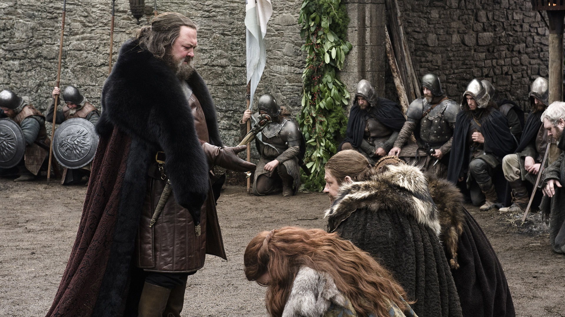 A character in Game of Thrones extends his hand to a group of kneeling people