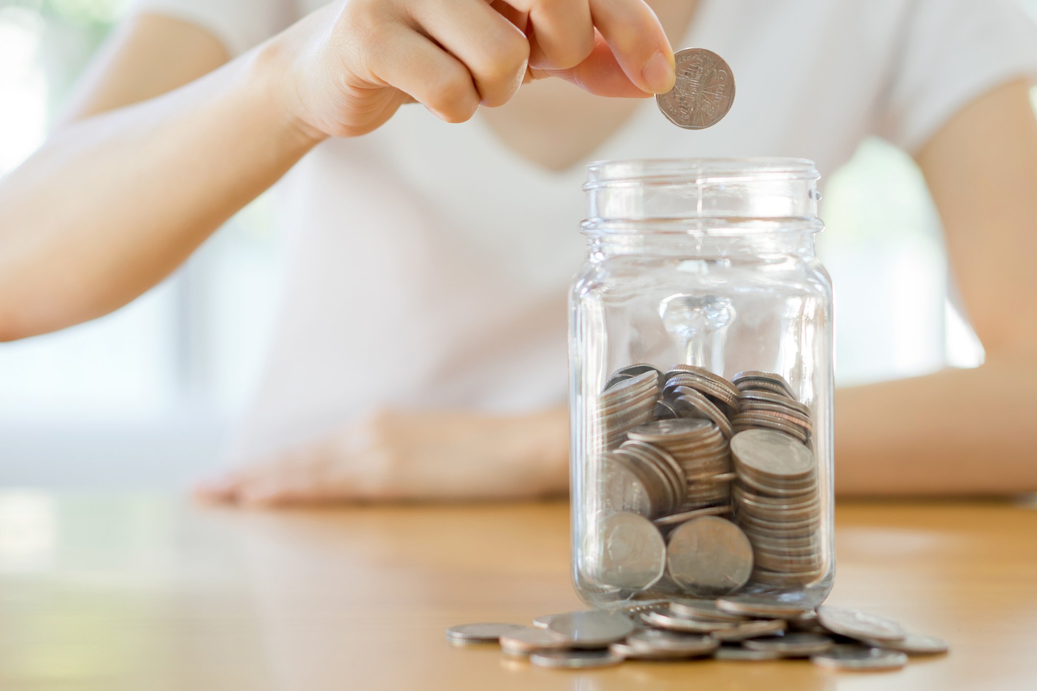 Person putting coins into a jar.