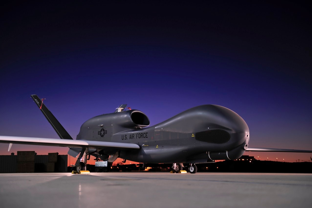 Global Hawk aircraft on the tarmac at an airport at night.