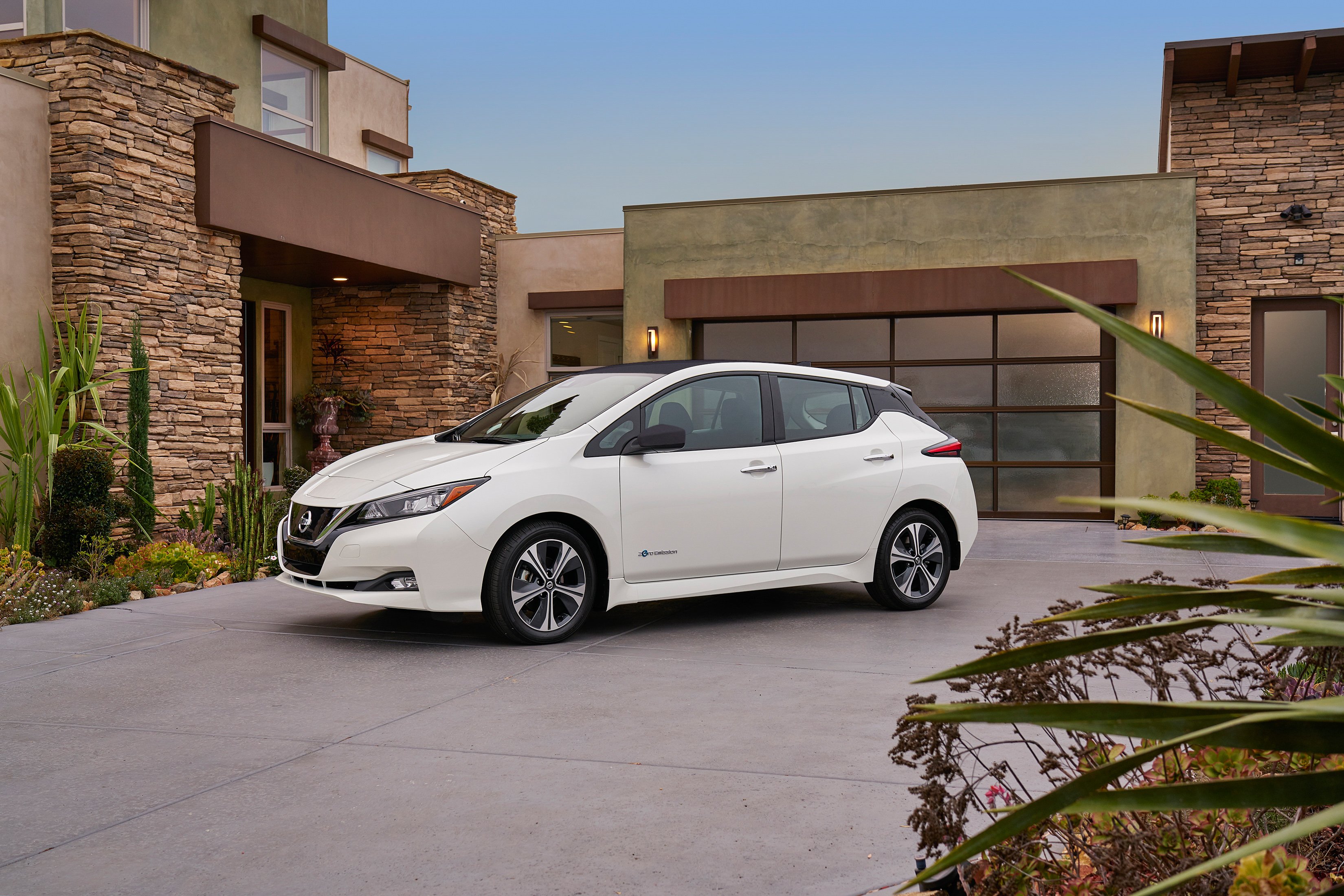 A white 2018 Nissan Leaf parked in a residential driveway.