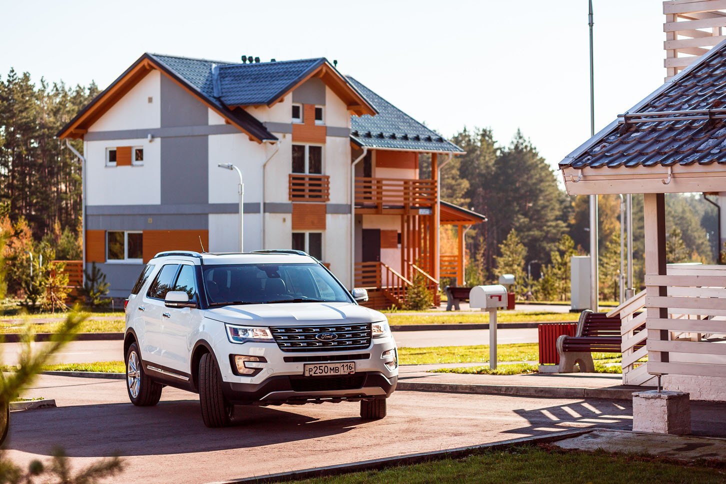 A white Ford Explorer with a Russian license plate in a Russian village.