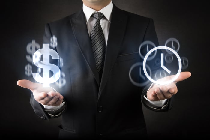 Man with hands facing up with dollar signs over one and clocks over the other