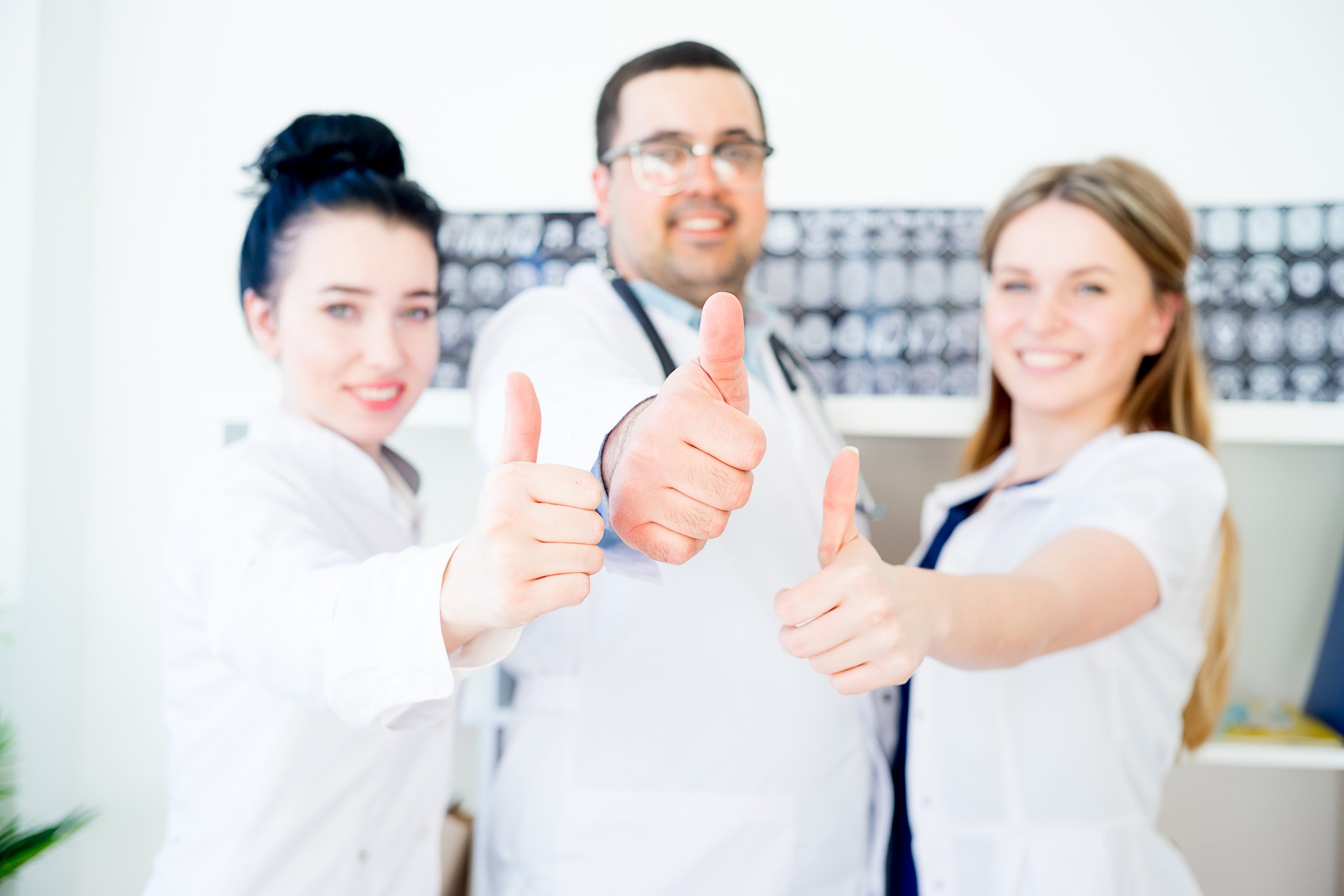 Three doctors making thumbs up gesture.