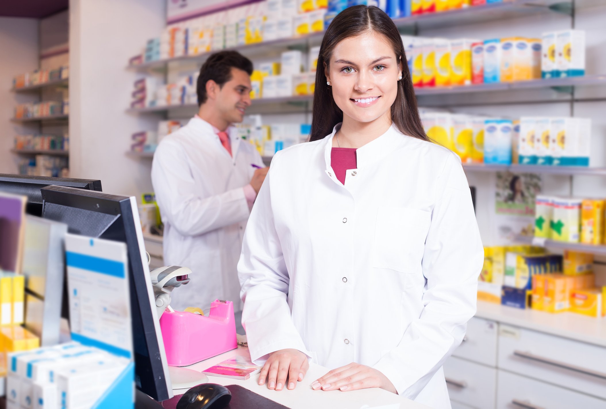 A pharmacist stands behind a drugstore counter.