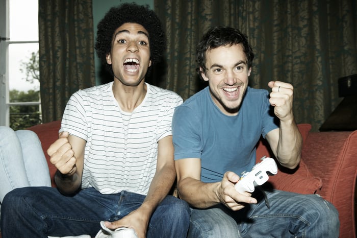 Two friends celebrating while playing a console game.