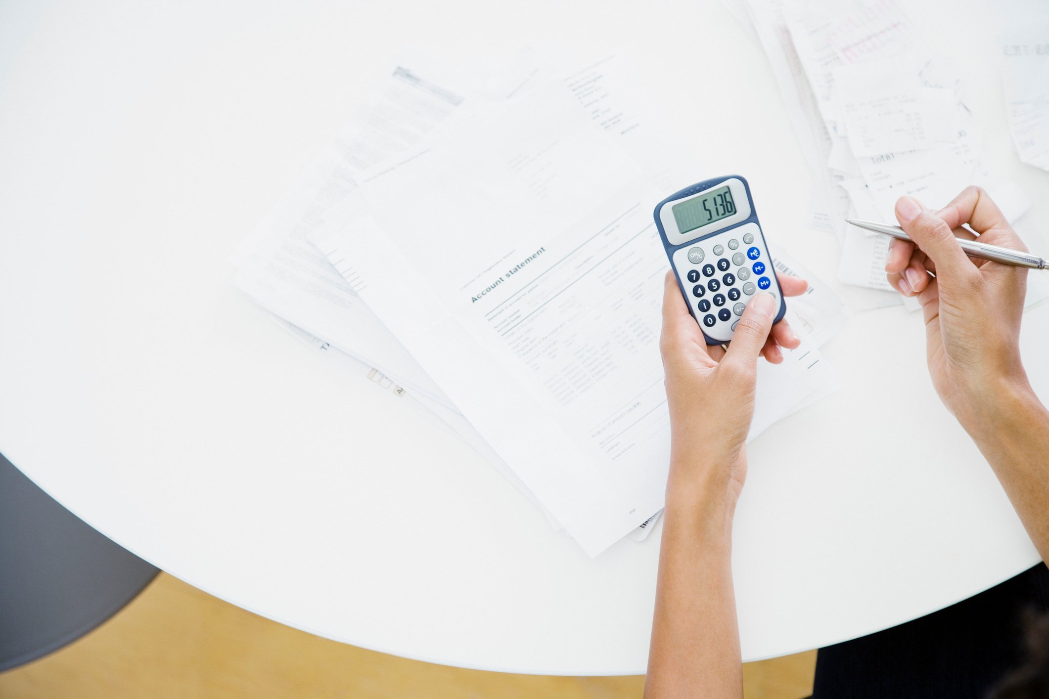 Person sitting at table using a calculator.