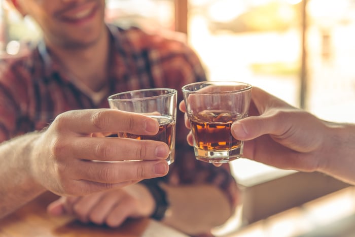 Friends in a cafe toasting each other with a shot of hard liquor. 