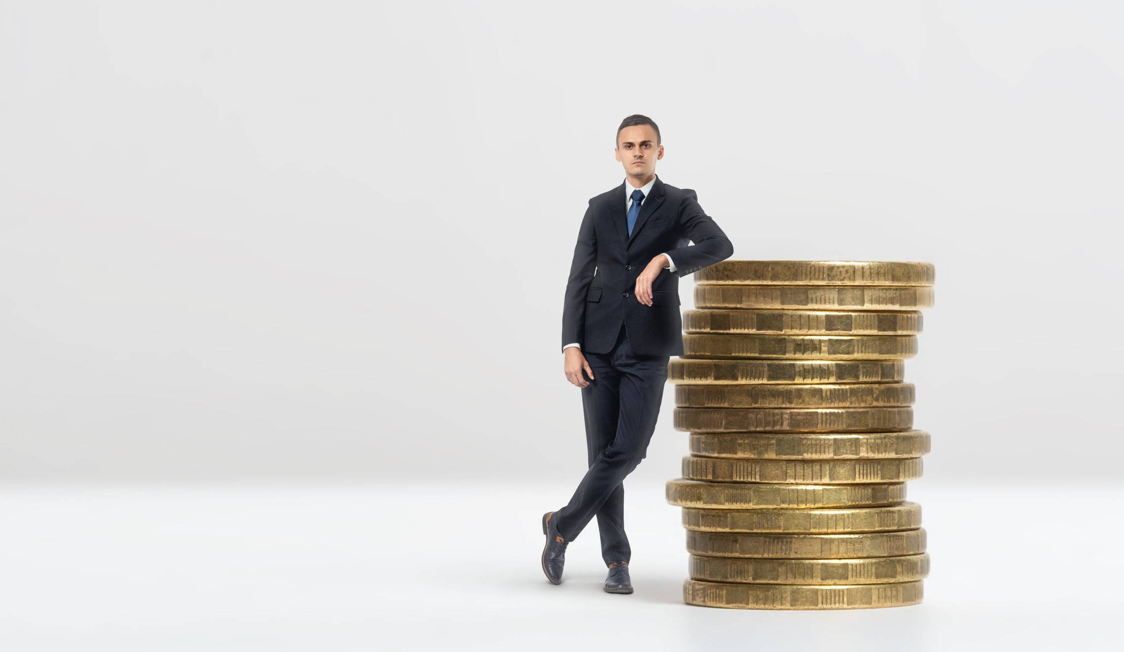 Businessman leaning on stack of giant gold coins
