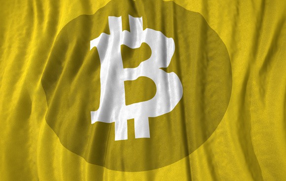 Bitcoin symbol on a flowing, curtain-like yellow background.