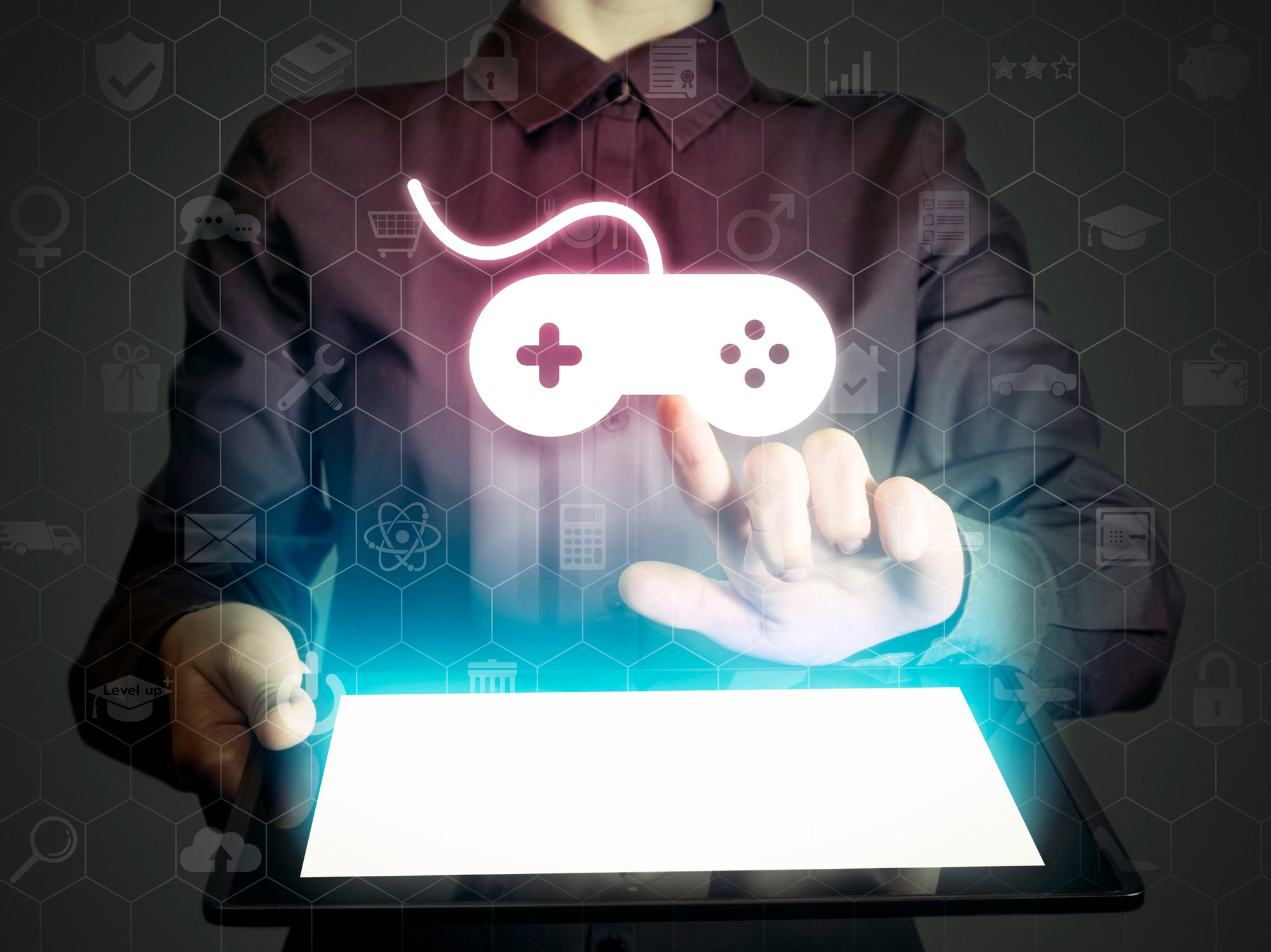 A person touching a video game controller icon that is being projected from a tablet.
