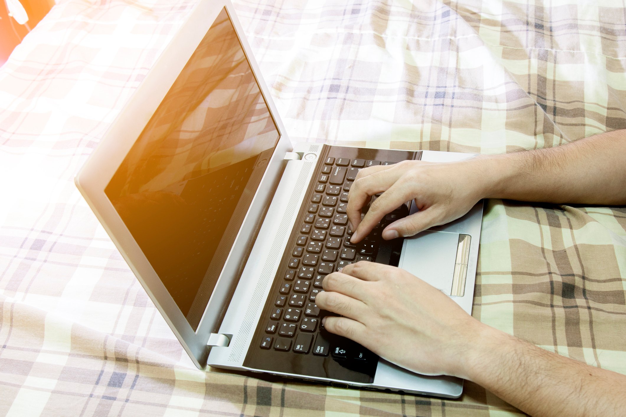 Typing on laptop in bed