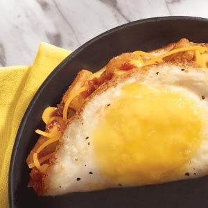 Burrito ingredients encased in a fried egg on skillet.