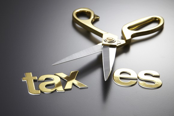 A pair of scissors cutting through the word "taxes"