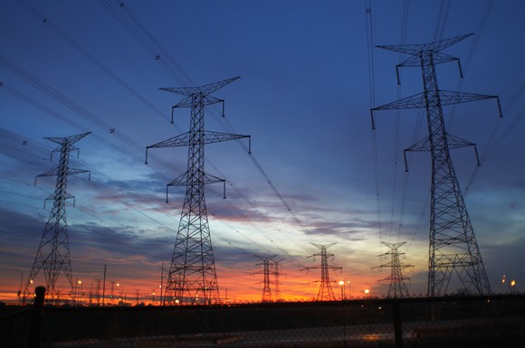 Huge transmission lines against a darkening sky.