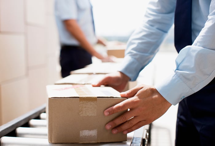 A man handles a box on a conveyor as it moves through a distribution facility.