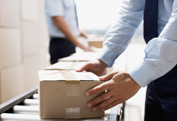 A man handles a box on a conveyor as it moves through a distribution facility.