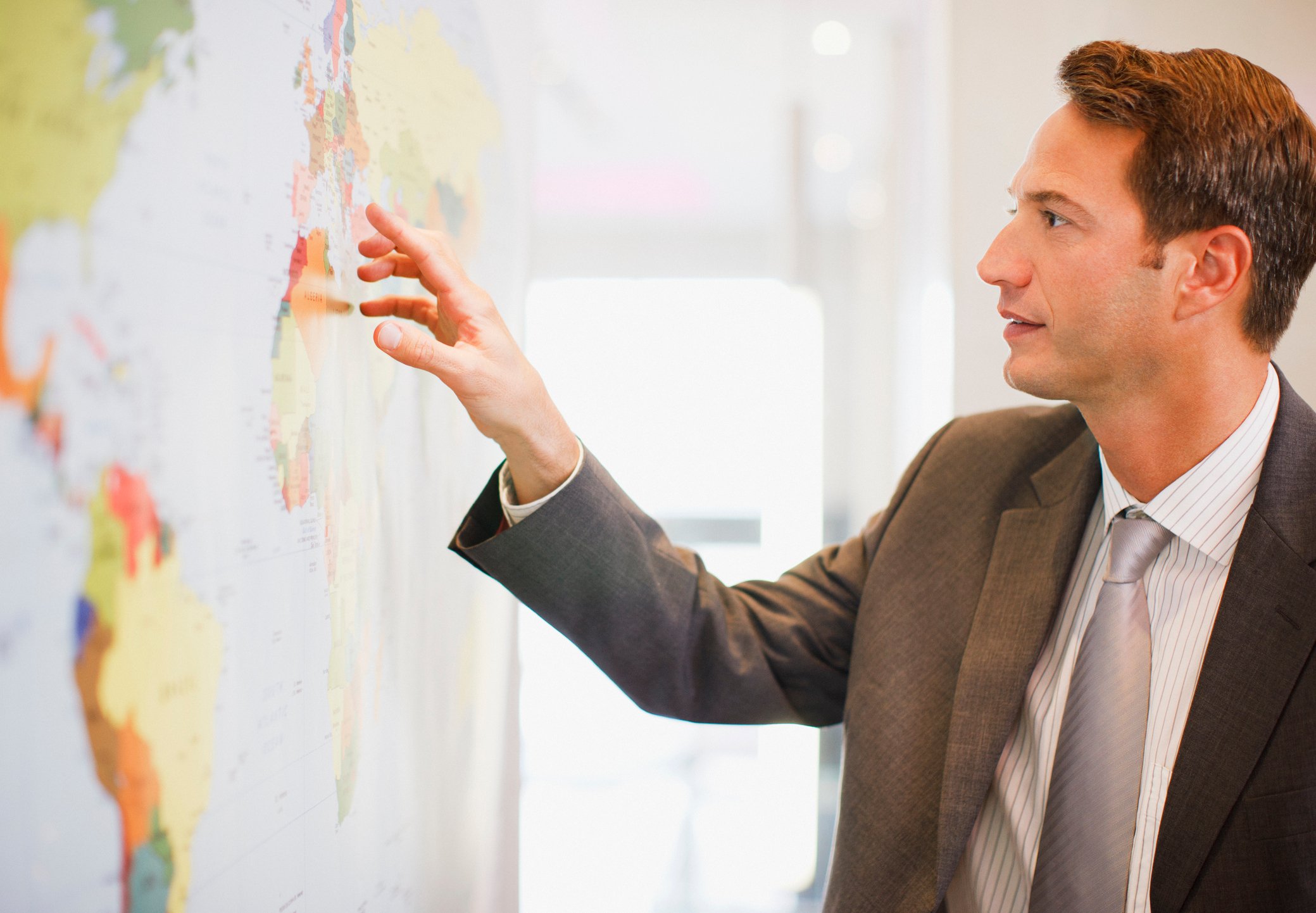 Man in suit looking at a world map.